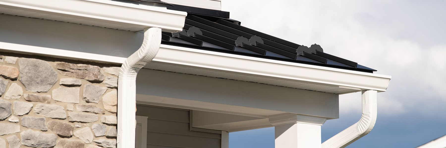 Overhead view of a house with a dark gray shingle roof, satellite dish, and American flag on the side.