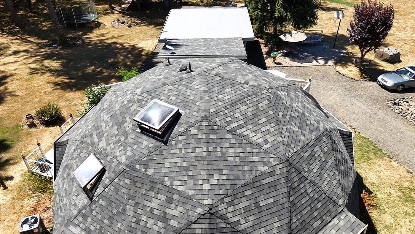 Overhead view of a house with a rounded roof covered in gray shingles. Skylights and vents are visible.