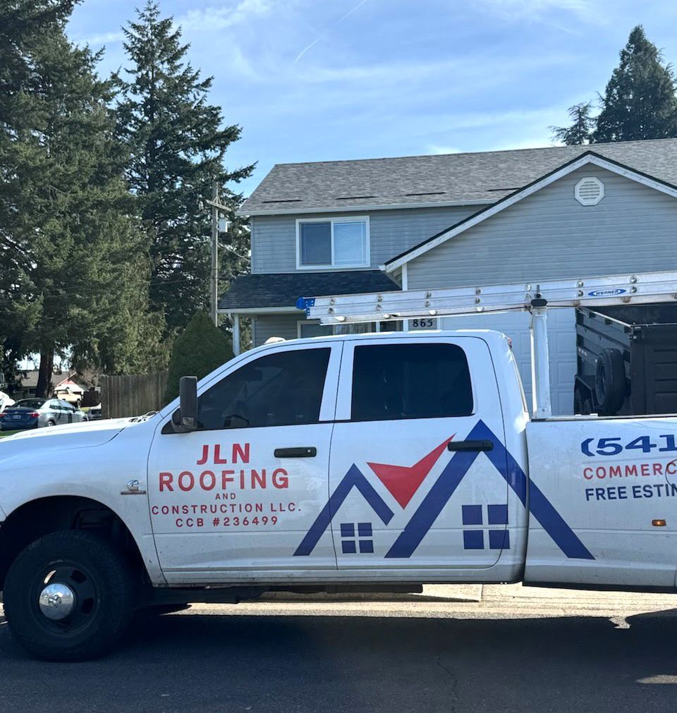 A jln roofing truck is parked in front of a house