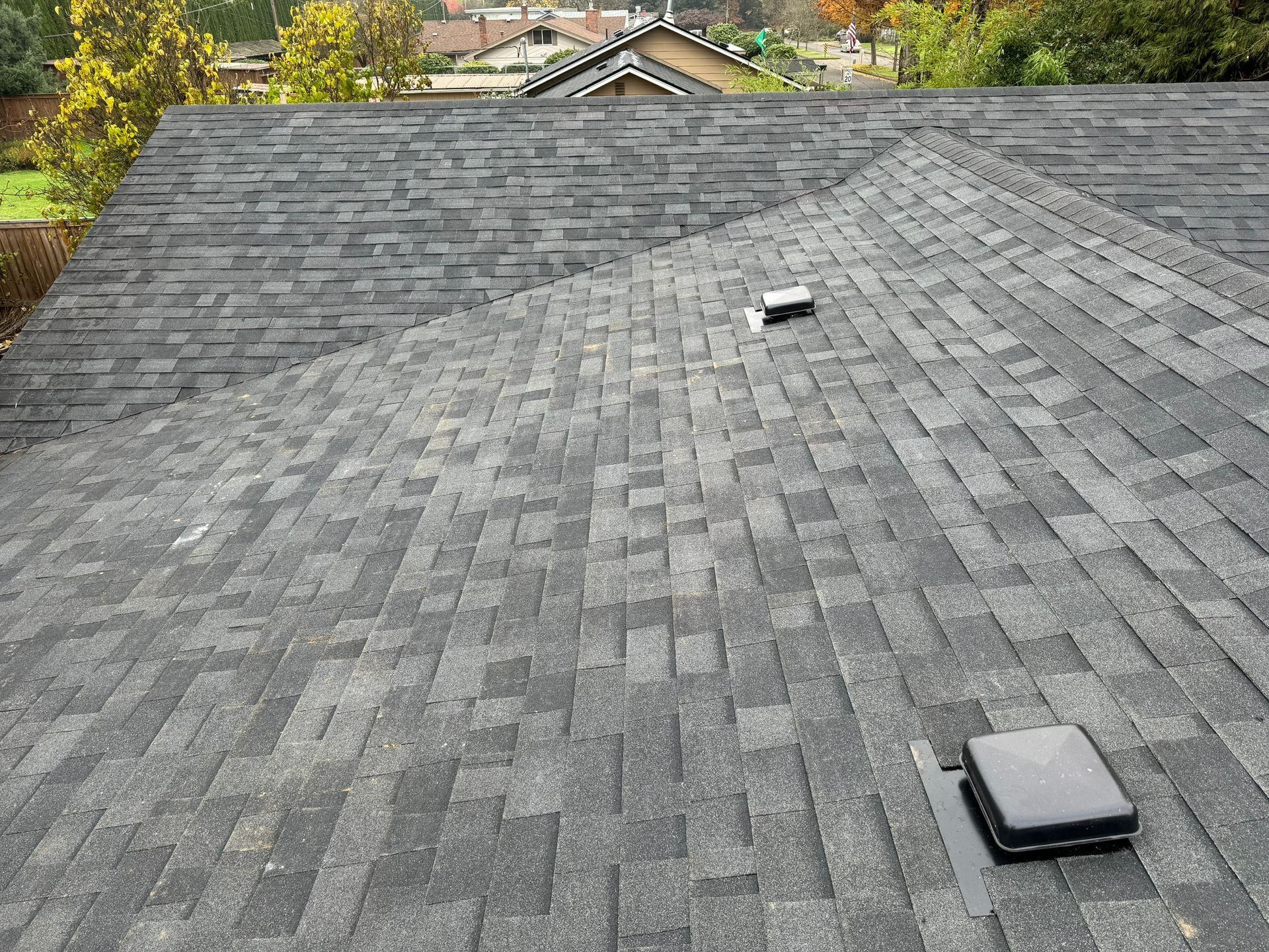 A close up of a roof with shingles and a vent on it.