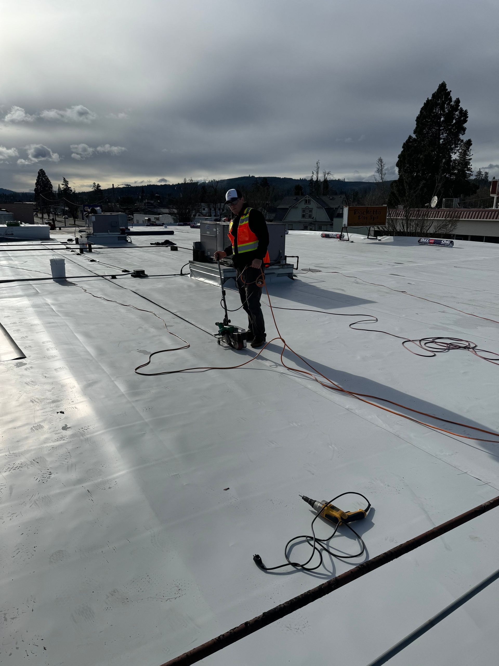 A man is standing on top of a snow covered roof.