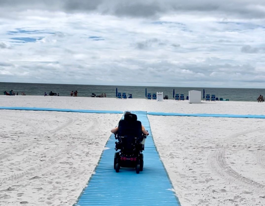 Wheelchair user enjoying use of Mobi-Mat for beach access at Gulf Shores, Alabama