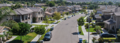 An aerial view of a residential neighborhood with cars parked on the side of the road.