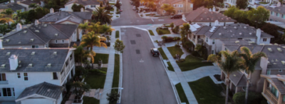 An aerial view of a residential neighborhood with a car driving down the street.