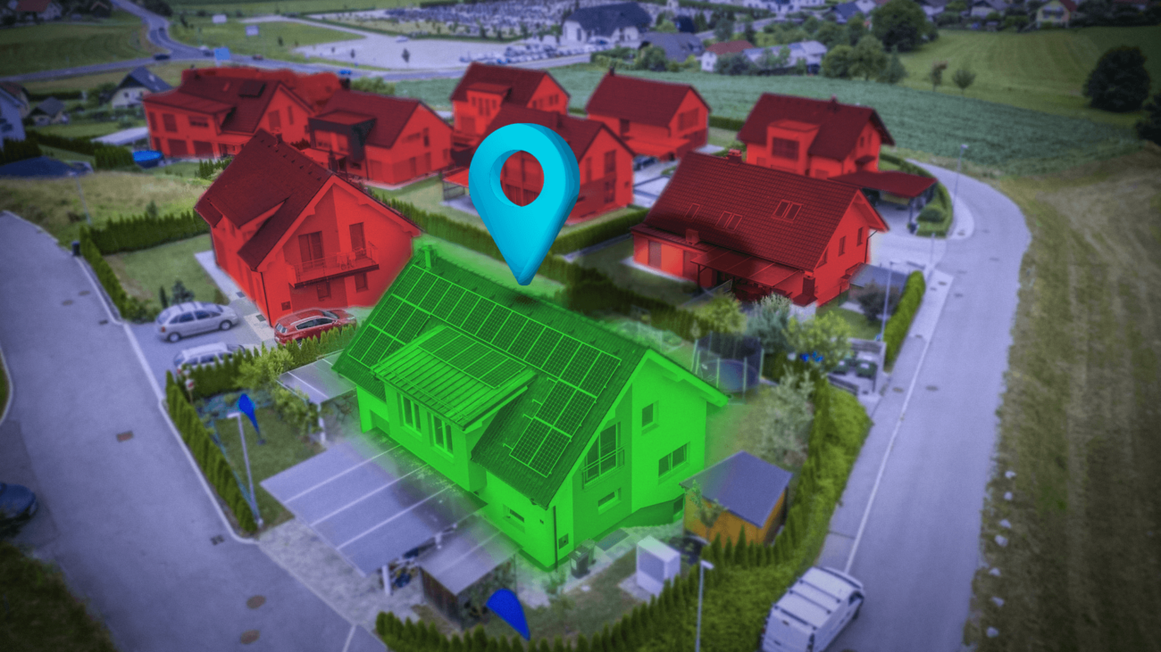 An aerial view of a residential area with a green house with solar panels on the roof.