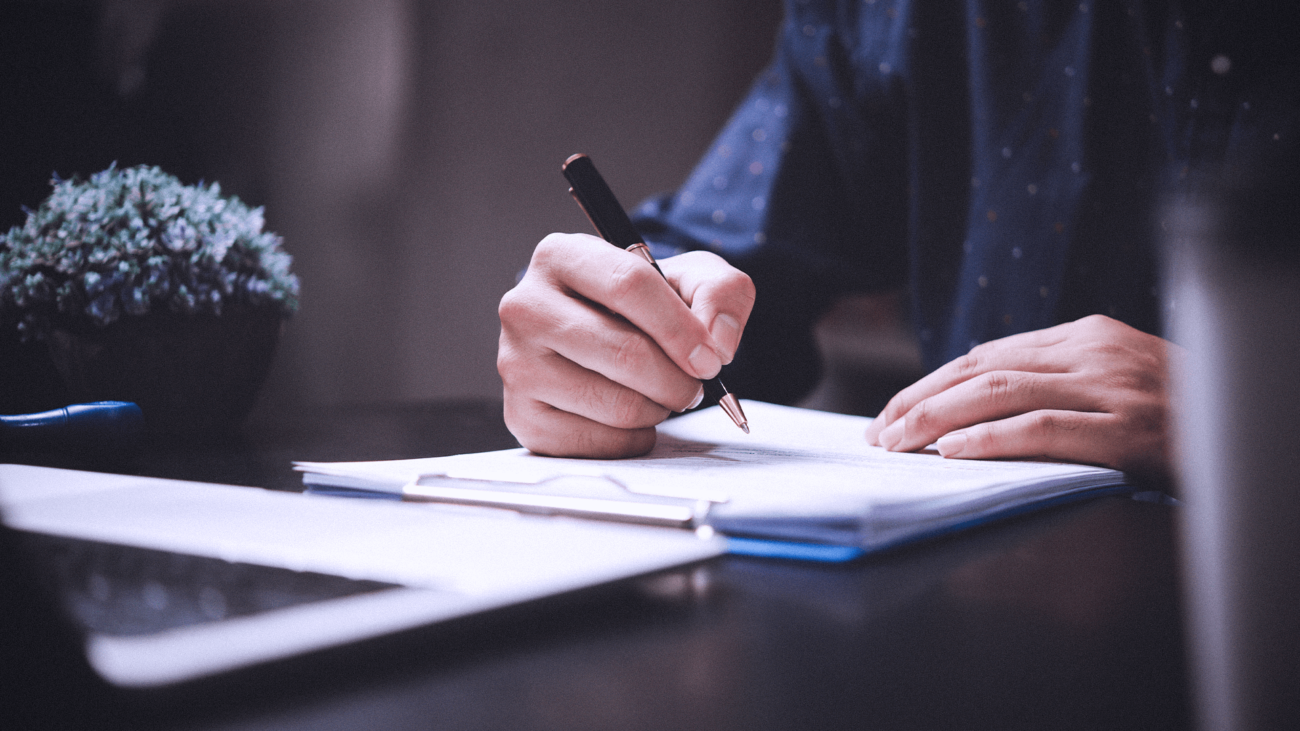 A person is writing on a piece of paper with a pen.