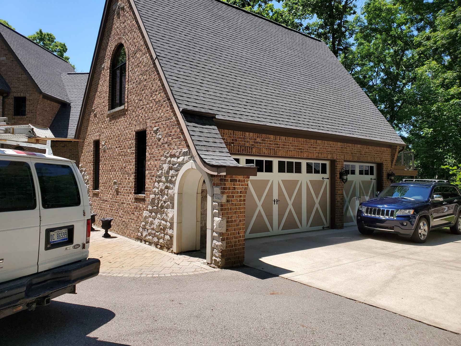 A white van is parked in front of a large brick garage.