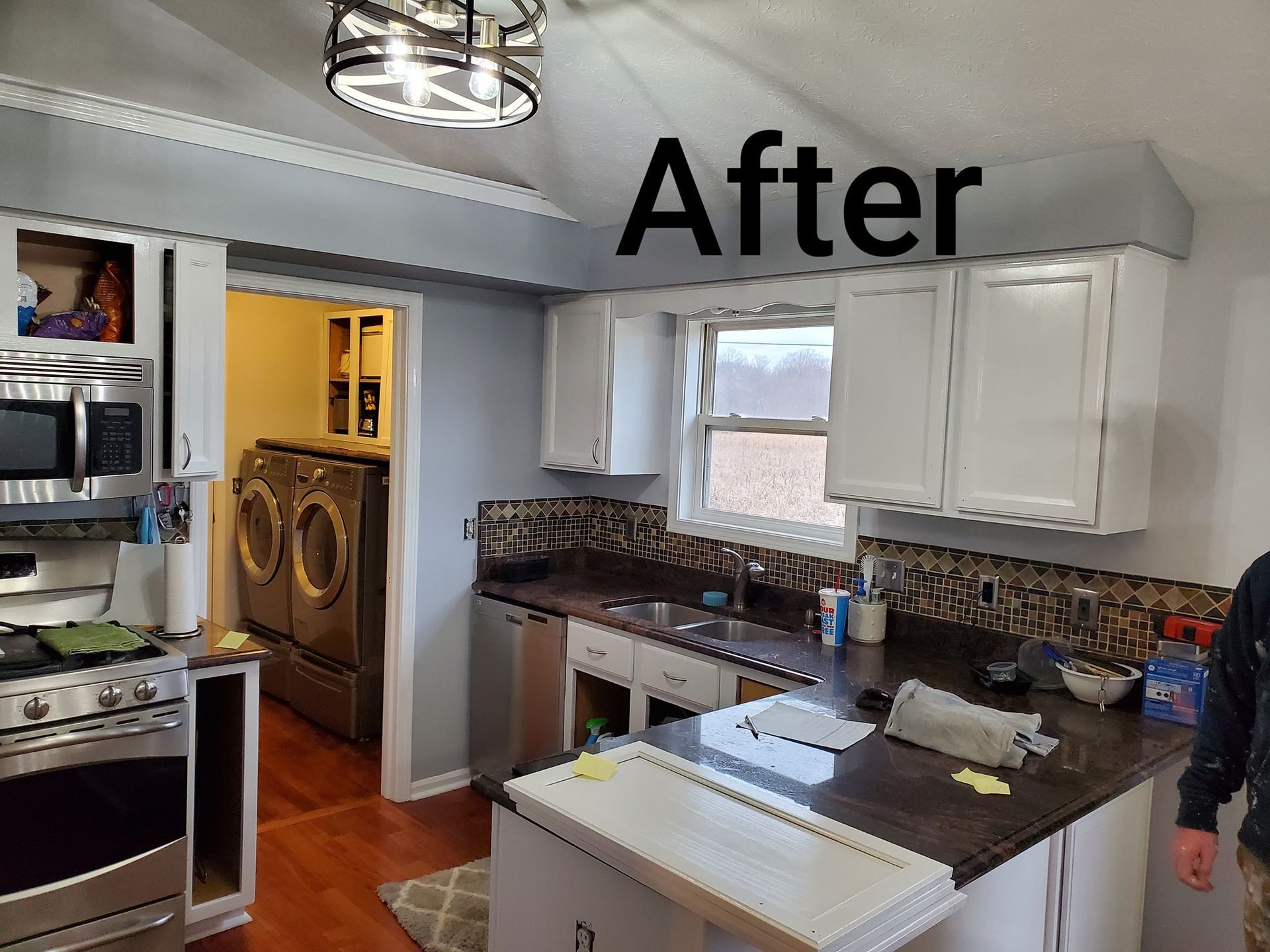 A kitchen with white cabinets and stainless steel appliances and a sign that says after