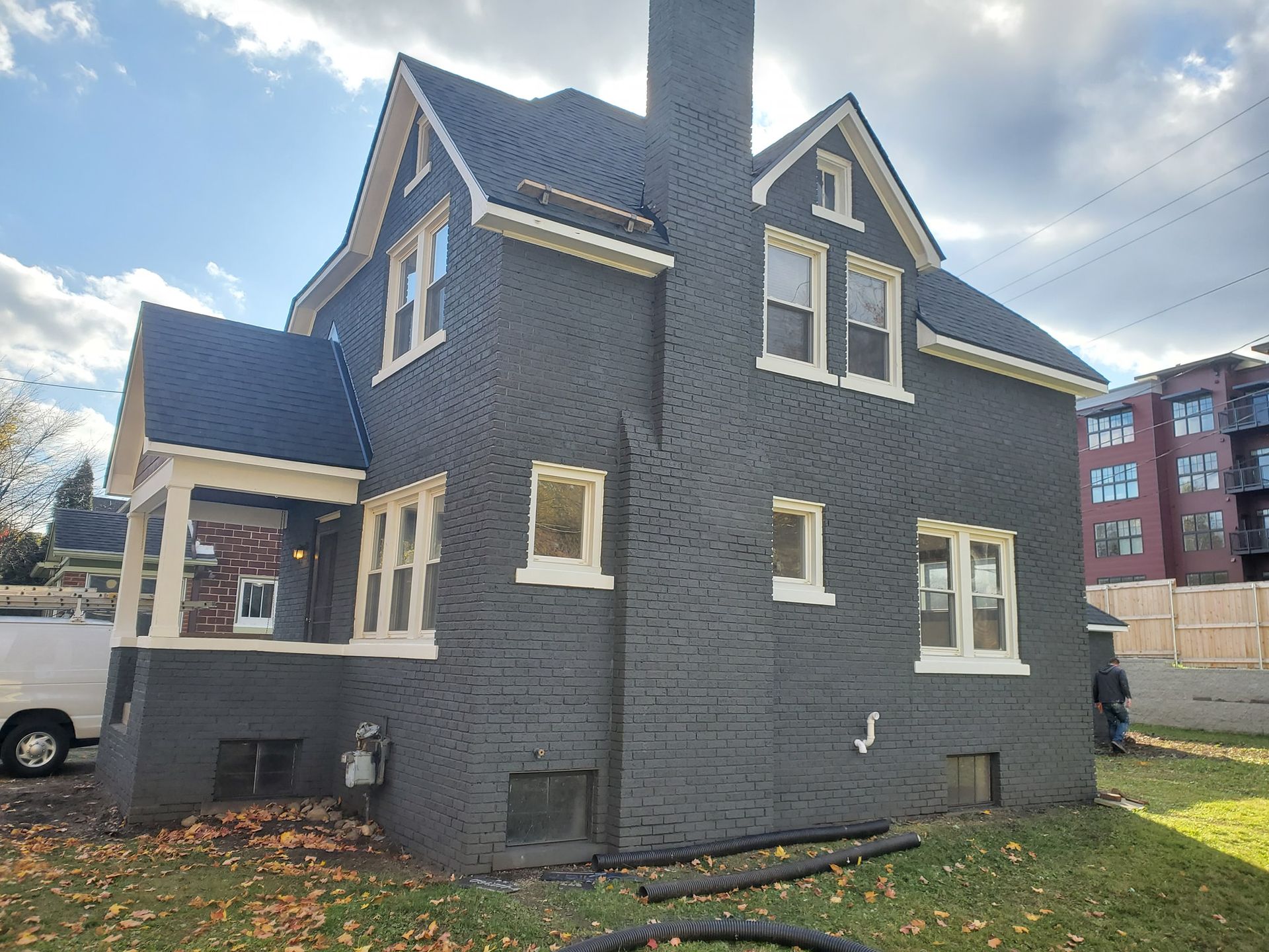 A large black brick house with a blue roof is being built.