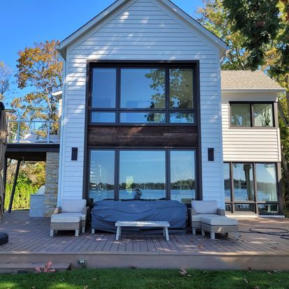 A white house with a lot of windows and a couch on the deck