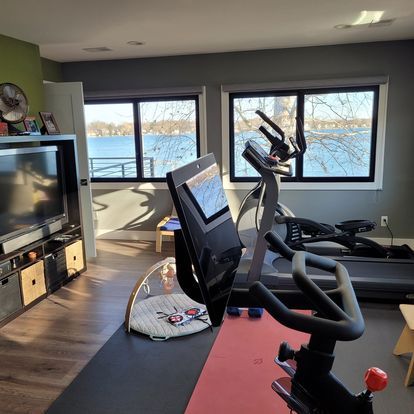 A living room with a bicycle , treadmill , and television.