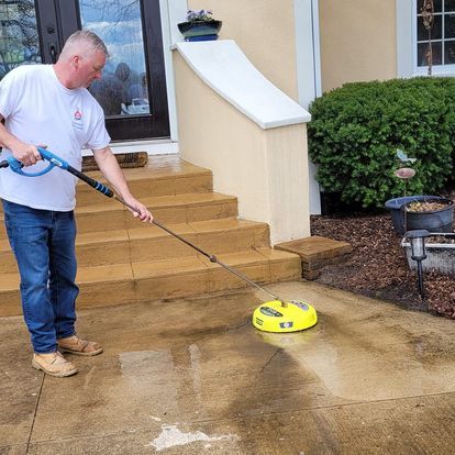 A man is cleaning a patio with a pressure washer.