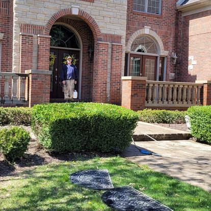A man is standing in front of a large brick house.