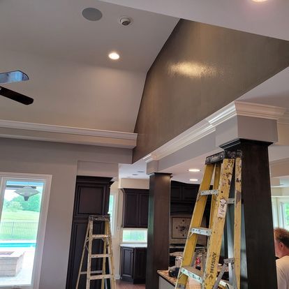A man is standing next to a ladder in a kitchen.