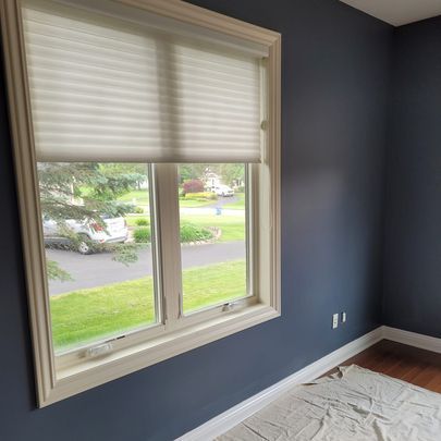 A room with blue walls and a window with white blinds.