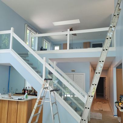 A ladder is leaning against the railing of a staircase in a house.