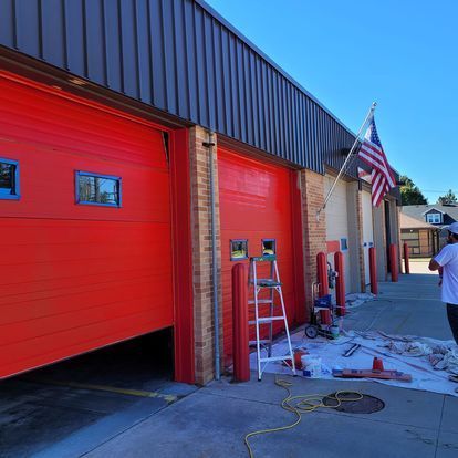 A man is standing in front of a red garage door.