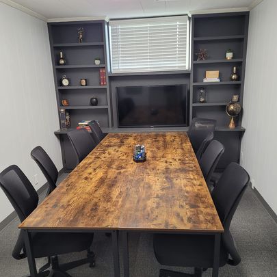 A conference room with a long table and chairs and a flat screen tv.