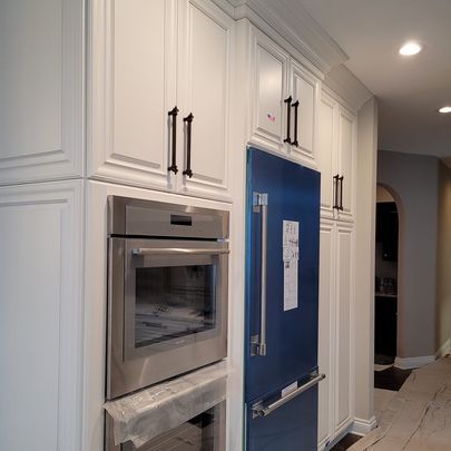 A kitchen with white cabinets , stainless steel appliances , and a blue refrigerator.