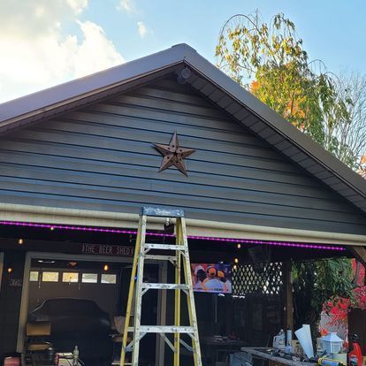 A ladder is sitting in front of a garage with a star on the roof.