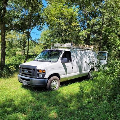 A white van is parked in the middle of a grassy field.