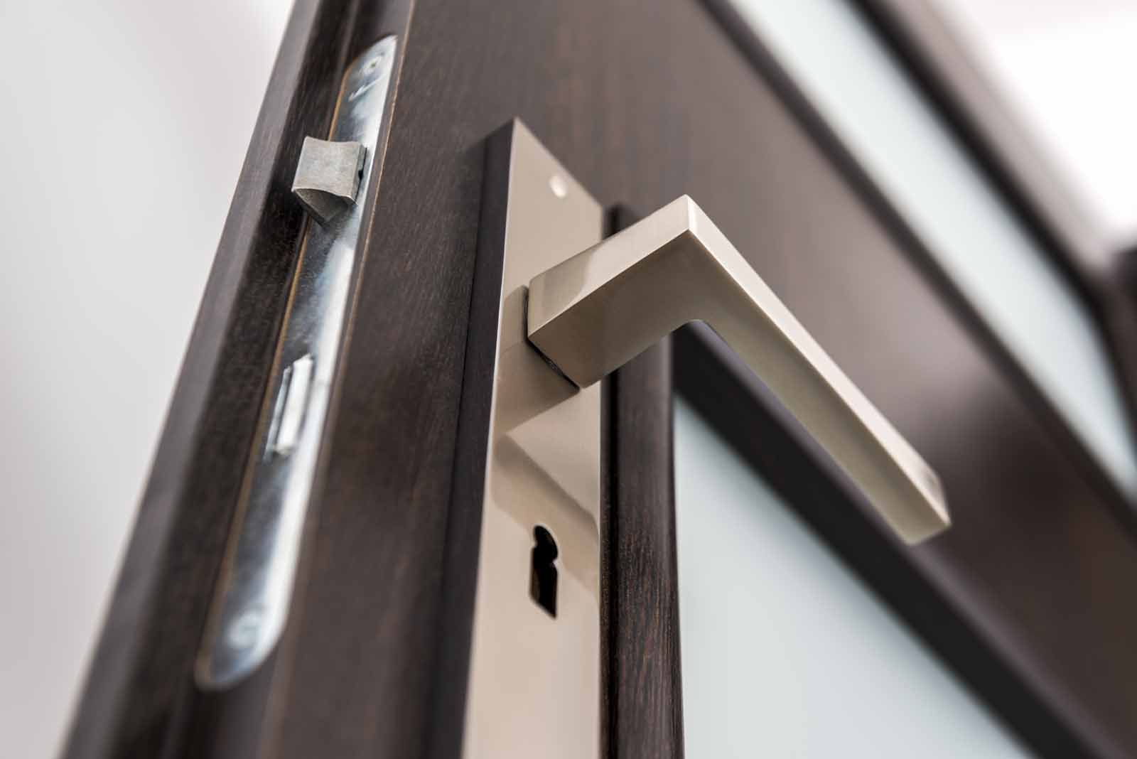 A close up of a door handle on a wooden door.