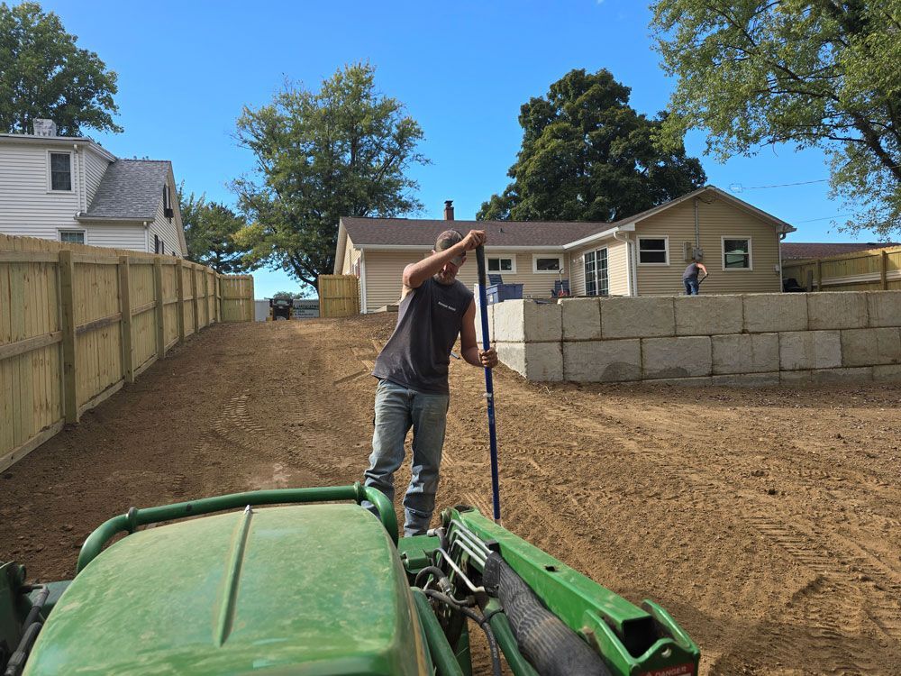 Gravel driveway between two houses with a tree-trimming machine and a trailer.