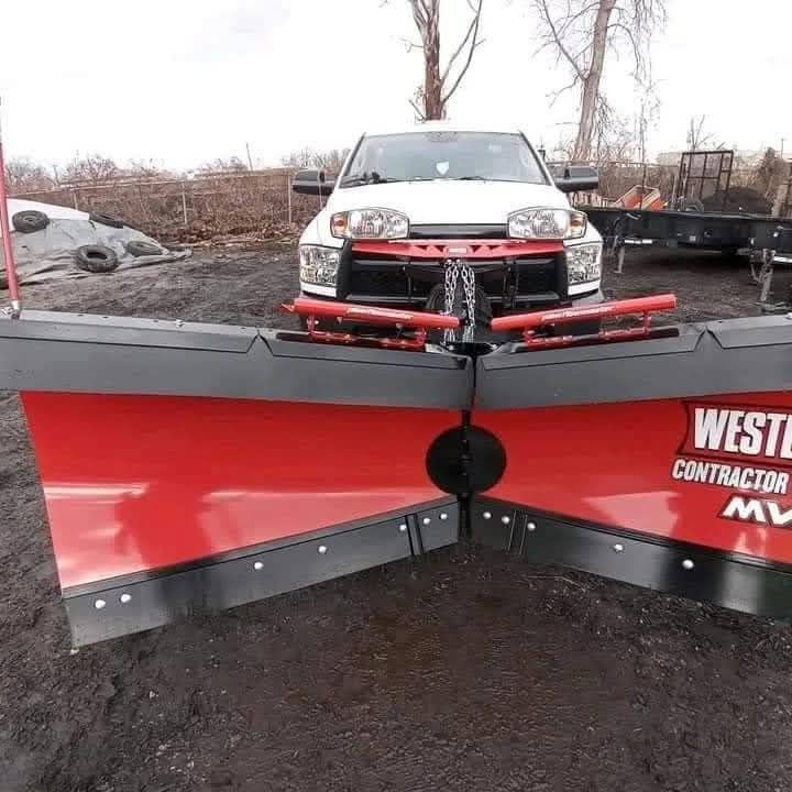 White truck with red snowplow, parked outside.