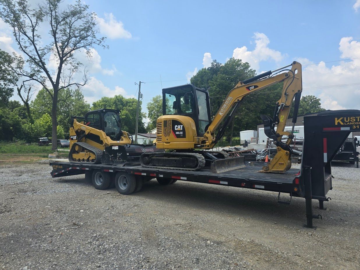 Yellow construction equipment, including an excavator and a skid steer, on a trailer.