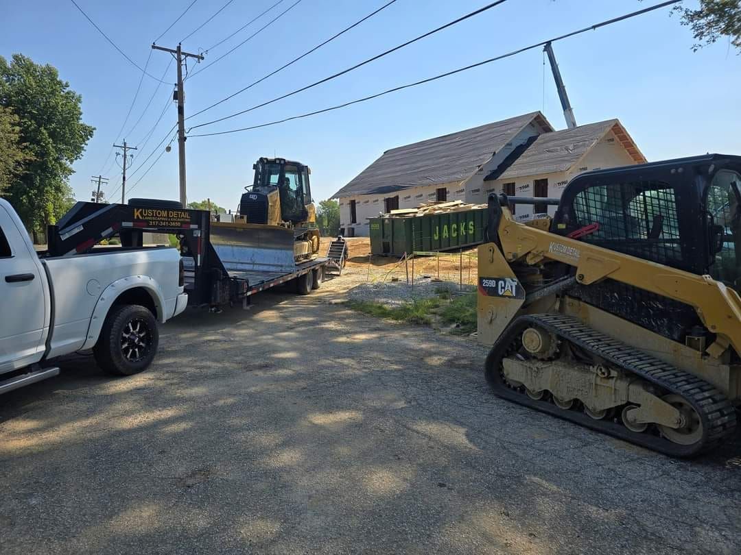 Construction site with heavy machinery and a partially built house under a blue sky.