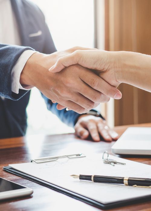 A man and a woman are shaking hands over a table.
