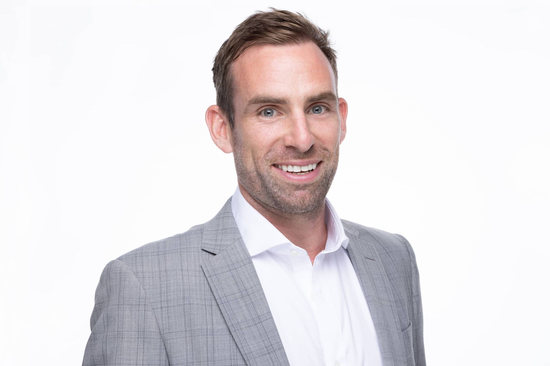 David Bell in a suit and white shirt smiling for the camera