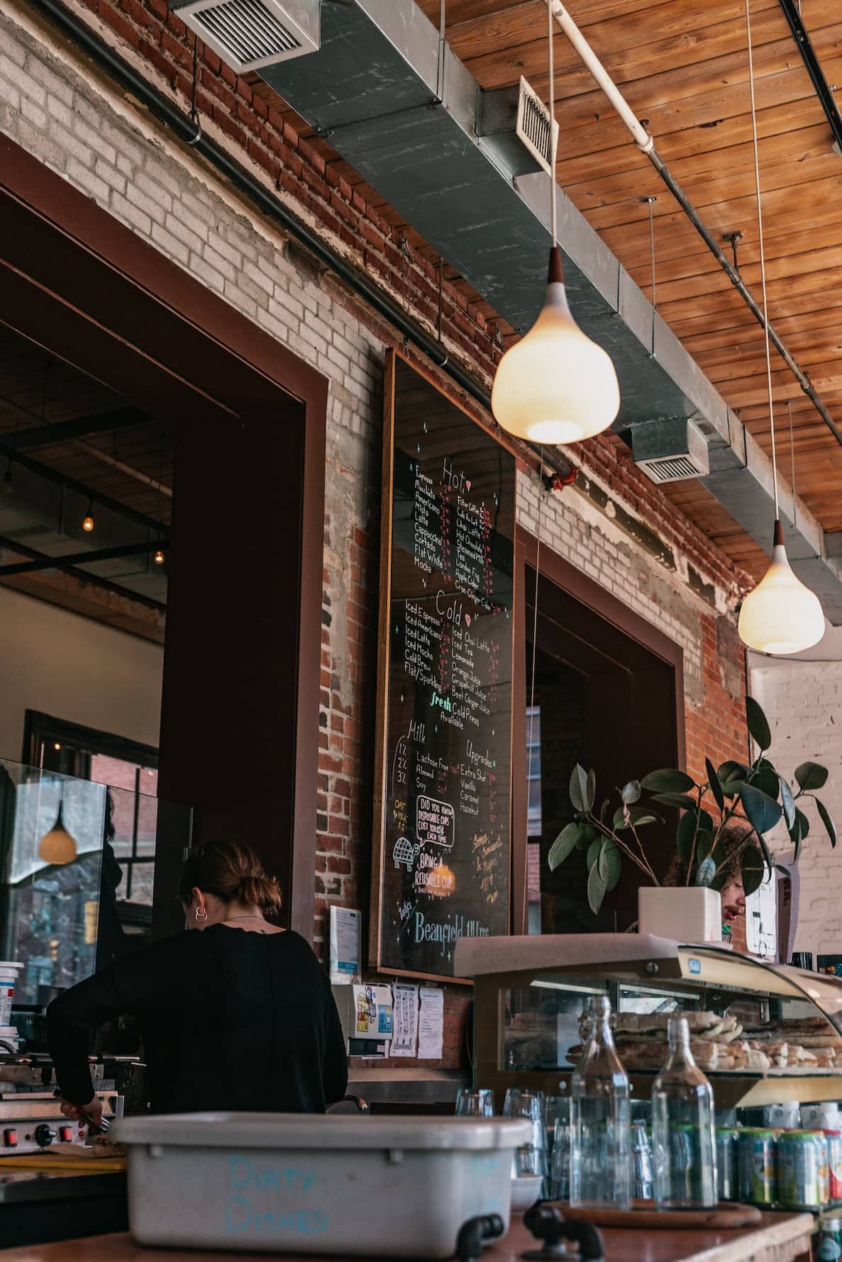 a woman behind a counter in a restaurant with a menu on the wall - commercial loan
