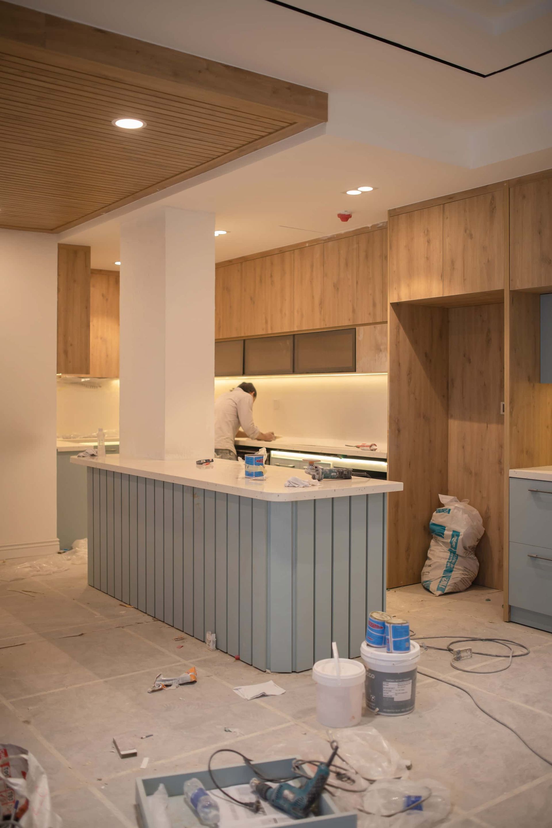 a man is working in a kitchen with blue cabinets - renovation loans gold coast