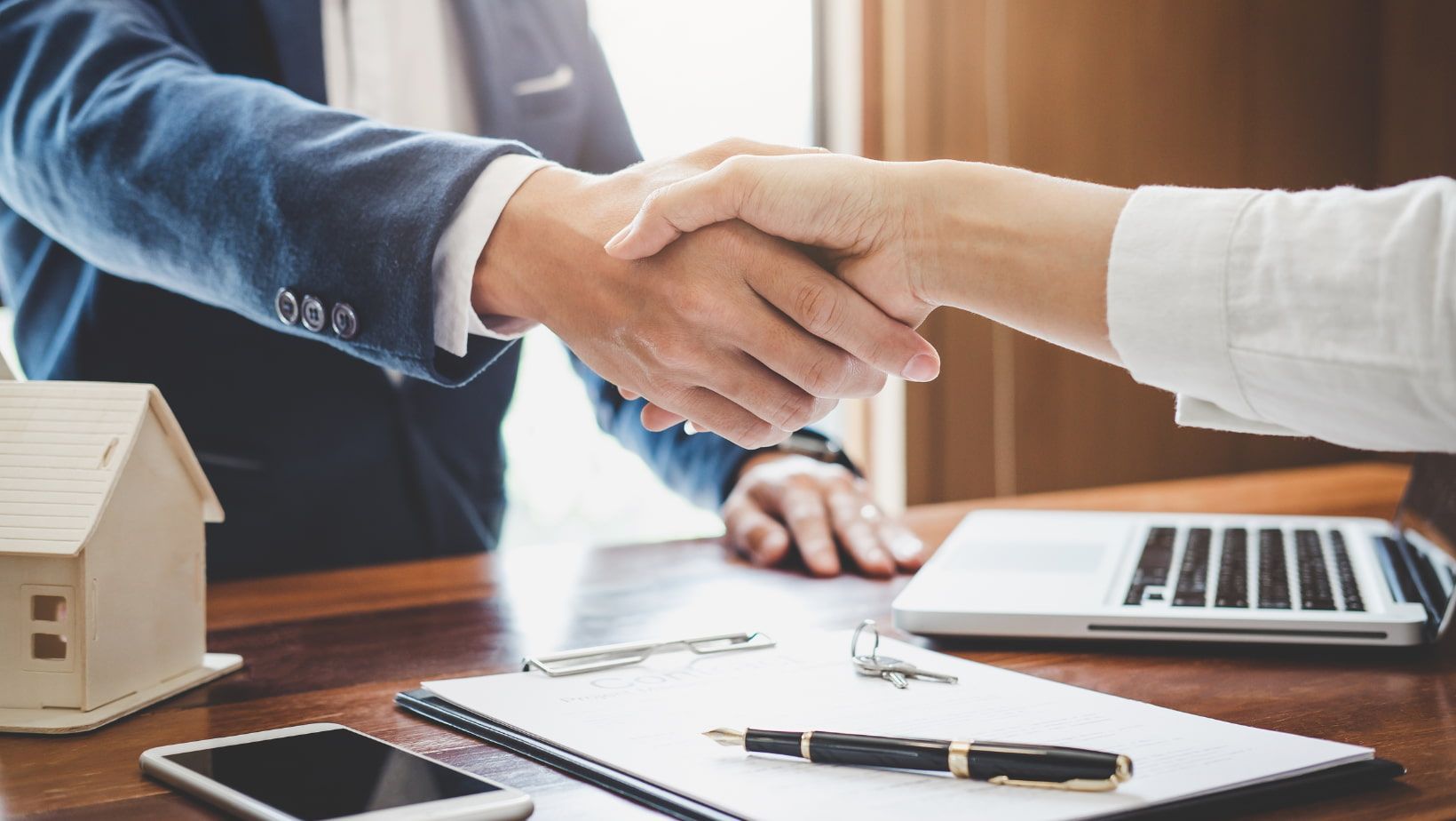 Two people shaking hands with suits on.