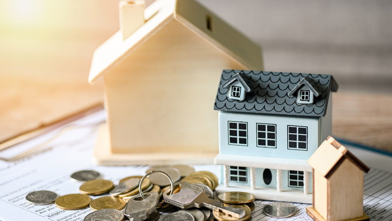 A model house is sitting on top of a pile of coins.