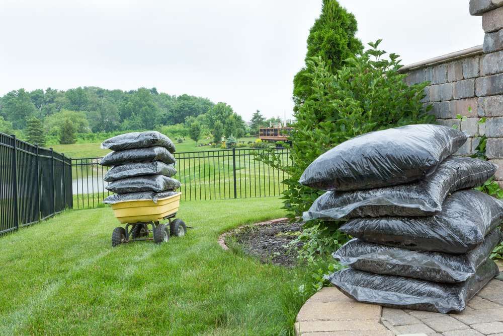 A Stack Of Bags Of Dirt Is Sitting Next To A Wheelbarrow Filled With Bags Of Dirt — HKL Landscape Supplies in Tuncurry, NSW 