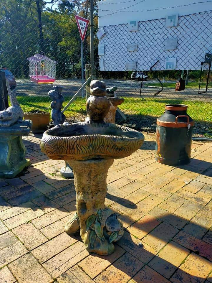 A Bird Bath Is Sitting On A Brick Patio Next To A Fence — HKL Landscape Supplies in Taree South, NSW