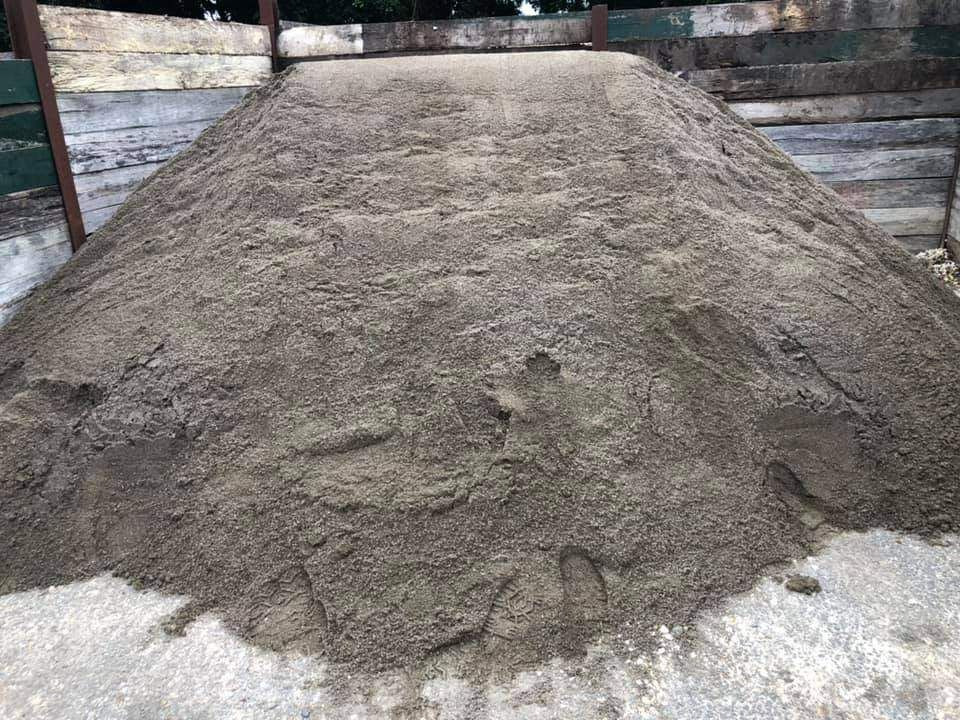 A Pile Of Dirt Is Sitting On The Ground In Front Of A Wooden Fence — HKL Landscape Supplies in Taree South, NSW