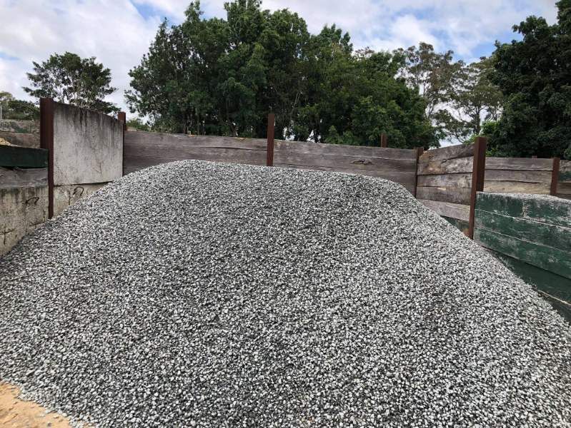 A Pile Of Gravel Is Sitting In Front Of A Wooden Fence — HKL Landscape Supplies in Taree South, NSW