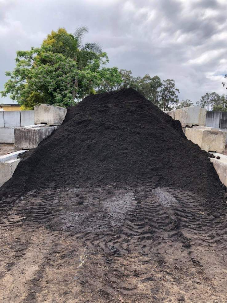 A Large Pile of Black Dirt is Sitting on the Ground in a Field — HKL Landscape Supplies in Smiths Lake, NSW