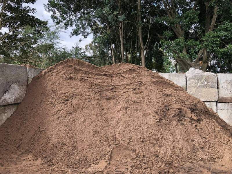 A Pile Of Dirt Is Sitting In Front Of A Brick Wall — HKL Landscape Supplies in Taree South, NSW