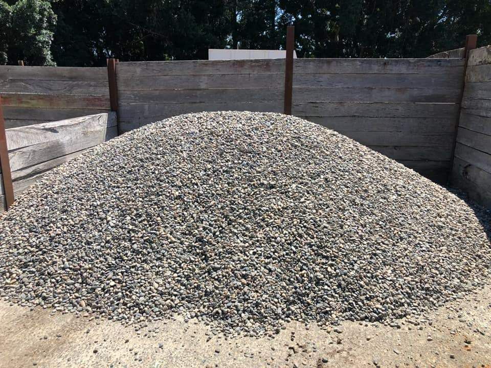 A Pile of Gravel is Sitting in Front of a Wooden Fence — HKL Landscape Supplies in Forster, NSW