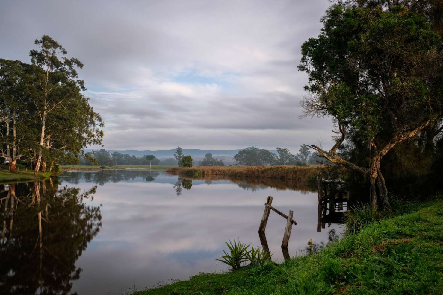A Lake Surrounded By Trees And Grass On A Cloudy Day — HKL Landscape Supplies in Bulahdelah, NSW 