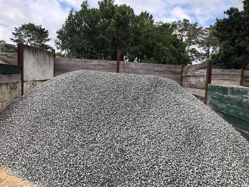 A Pile of Gravel is Sitting in Front of a Wooden Fence — HKL Landscape Supplies in Tuncurry, NSW 