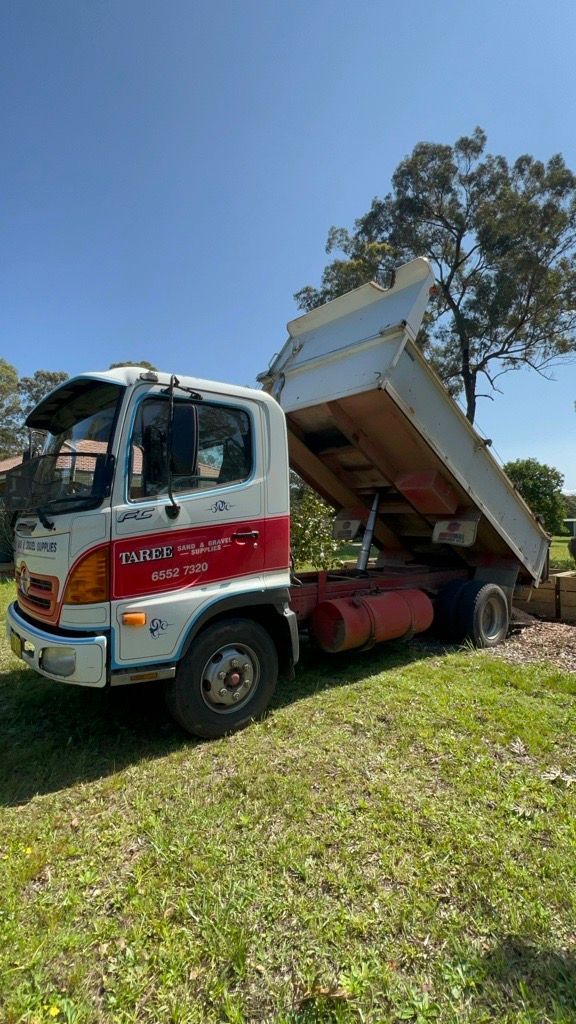 A White Dump Truck is Parked in a Grassy Field — HKL Landscape Supplies in Taree South, NSW