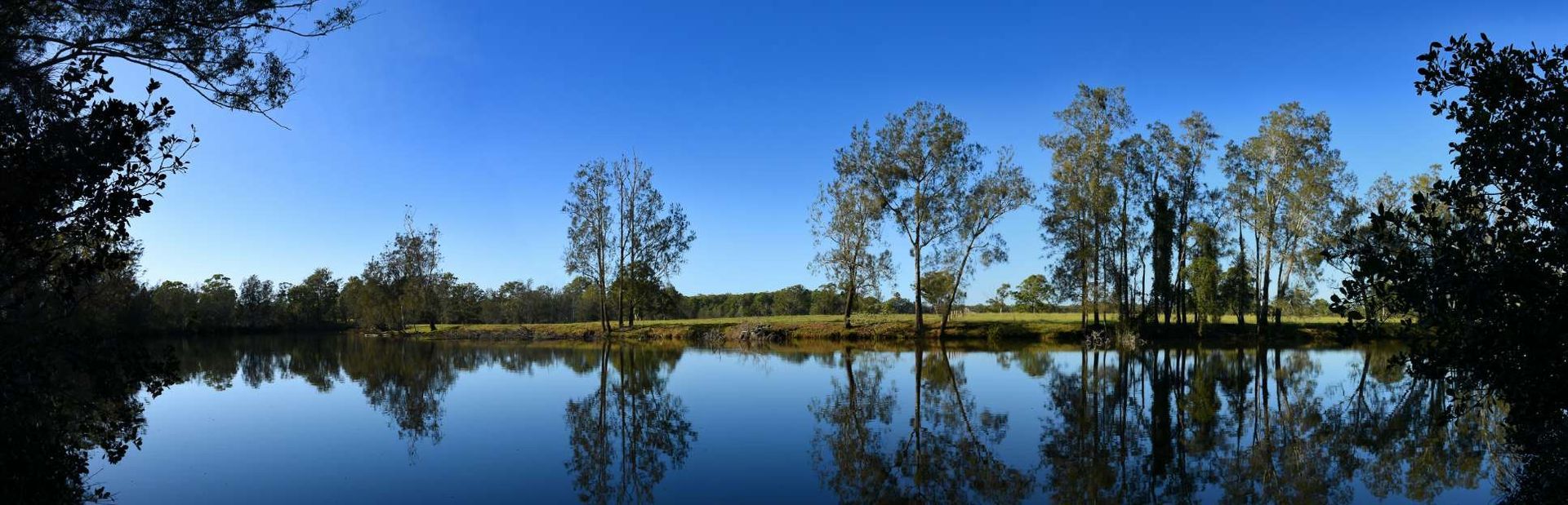 A Lake With Trees In The Background And A Blue Sky — HKL Landscape Supplies in Nabiac, NSW 