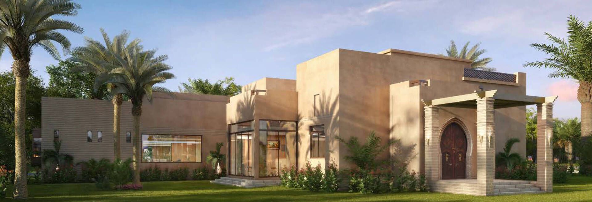 A desert-style building with palm trees, a grassy lawn, and a wooden arched doorway.