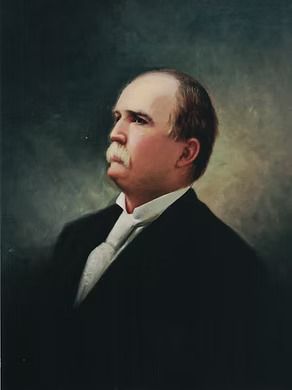 An oil portrait of a man with a mustache, wearing a dark suit and white collared shirt against a mottled dark background.