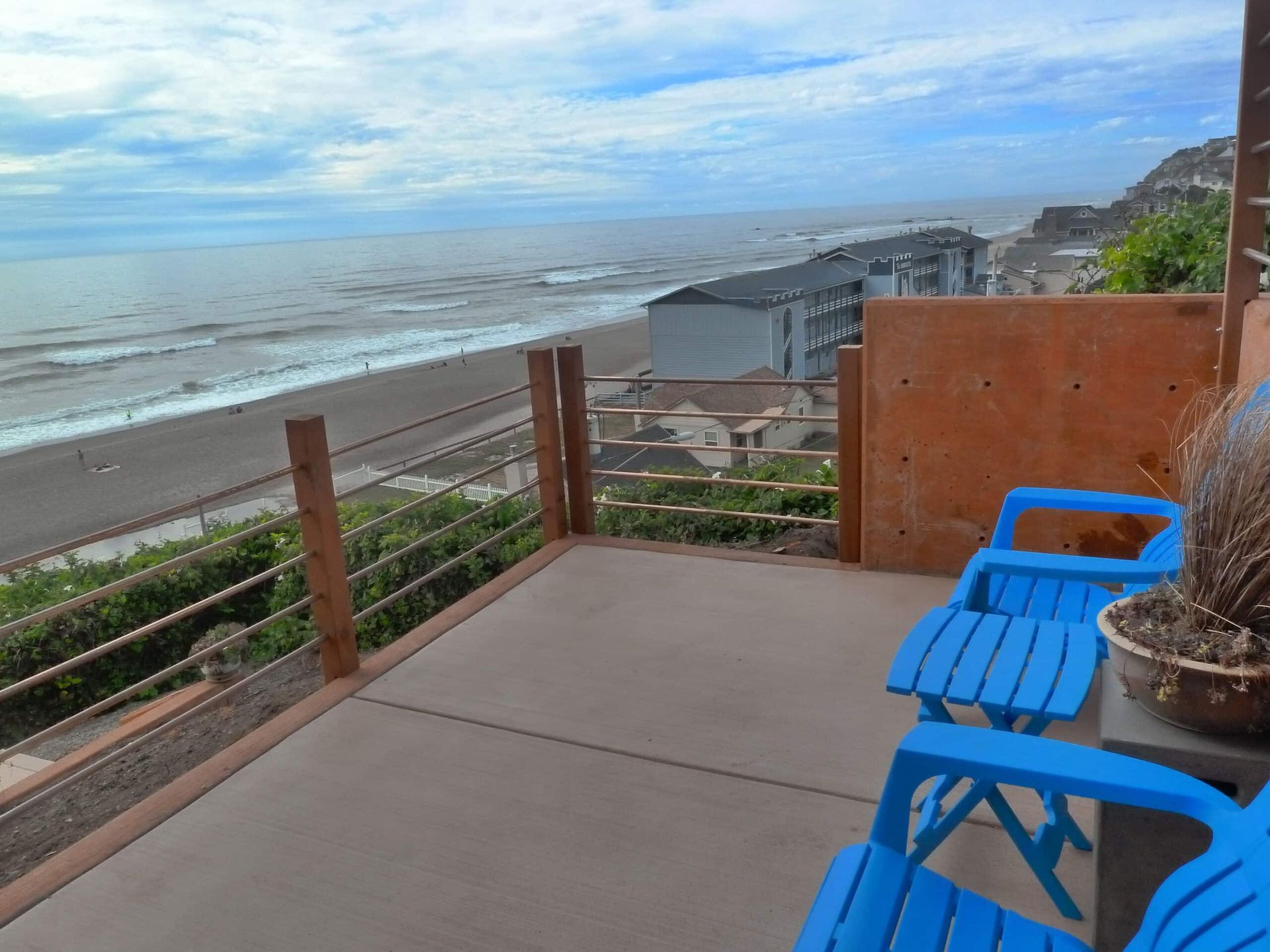 Two blue chairs on a balcony overlooking the ocean